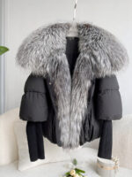 Schwarze, gesteppte Daunenjacke mit Strickärmeln und einem großen Kragen aus silbergrauem Fuchspelz. Sie ist auf einem Kleiderbügel vor einem weißen Sofa ausgestellt