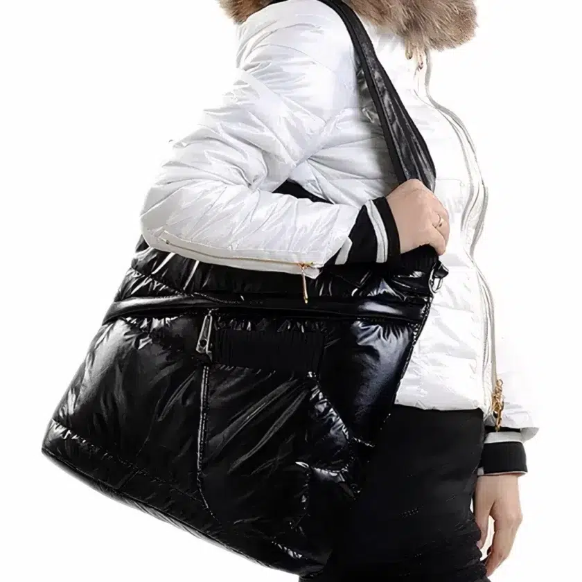 Gesichtslose Frau von der Seite mit einer weißen Daunenjacke mit braunem Pelz, die eine rechteckige schwarze Lacktasche über der Schulter trägt.