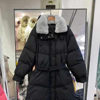 Gesteppte schwarze Daunenjacke mit grauem Pelzkragen und Gürtel in der Taille.
