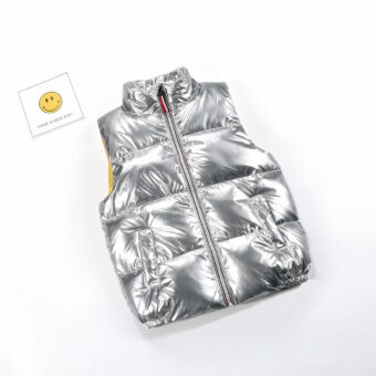 Foto einer ärmellosen silbernen Daunenjacke für Kinder mit einer Smiley-Karte daneben.