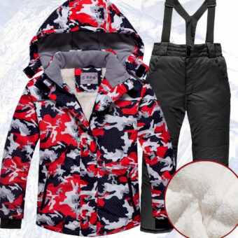 Set aus roter Ski-Daunenjacke mit Kapuze für Jungen und schwarzer Hose vor einer verschneiten Bergkulisse.