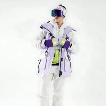 Frau in Skikleidung mit einer lila Ski-Daunenjacke, einer lila Mütze und einer lila Skibrille.