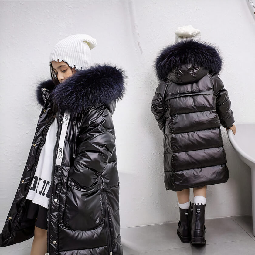 Teenager, der eine warme schwarze Daunenjacke in einem weißen Raum trägt.