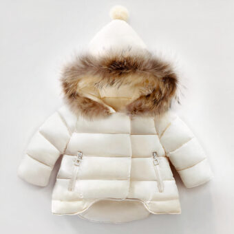 Sie sehen eine hübsche weiße Daunenjacke mit Pelz an der Kapuze. Sie ist gesteppt und die Kapuze ist spitz mit einem Pompon. Das Kleidungsstück wird auf weißem Hintergrund präsentiert.