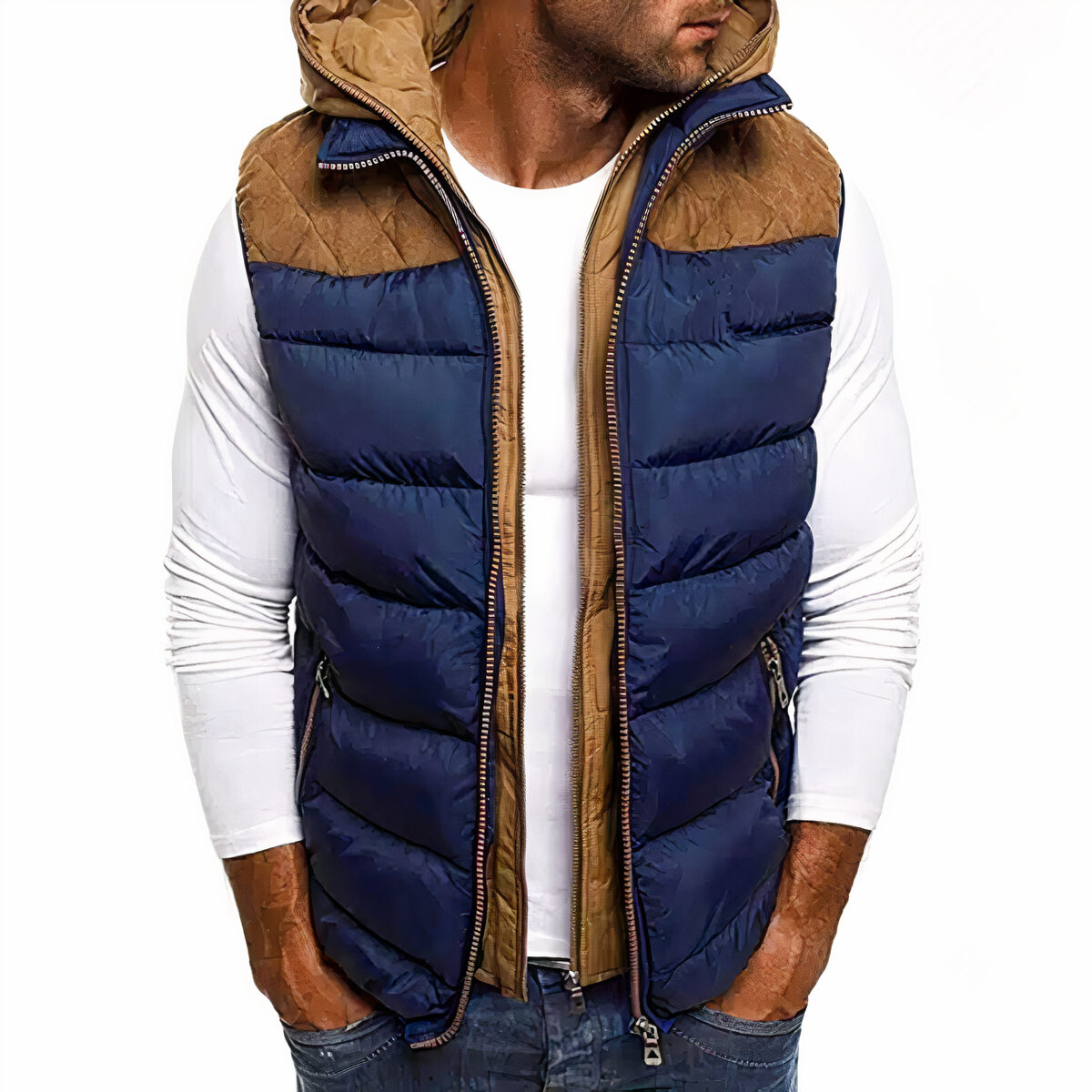 Mann mit einem weißen Oberteil und einer blauen und braunen Daunenjacke darüber. Er steht frontal und hat die Hände in den Taschen.