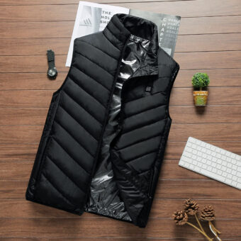 Ärmellose, elektrisch beheizbare Winterjacke in Schwarz, die auf einem Holzboden steht, mit einer Pflanze daneben und anderen Kleinigkeiten.