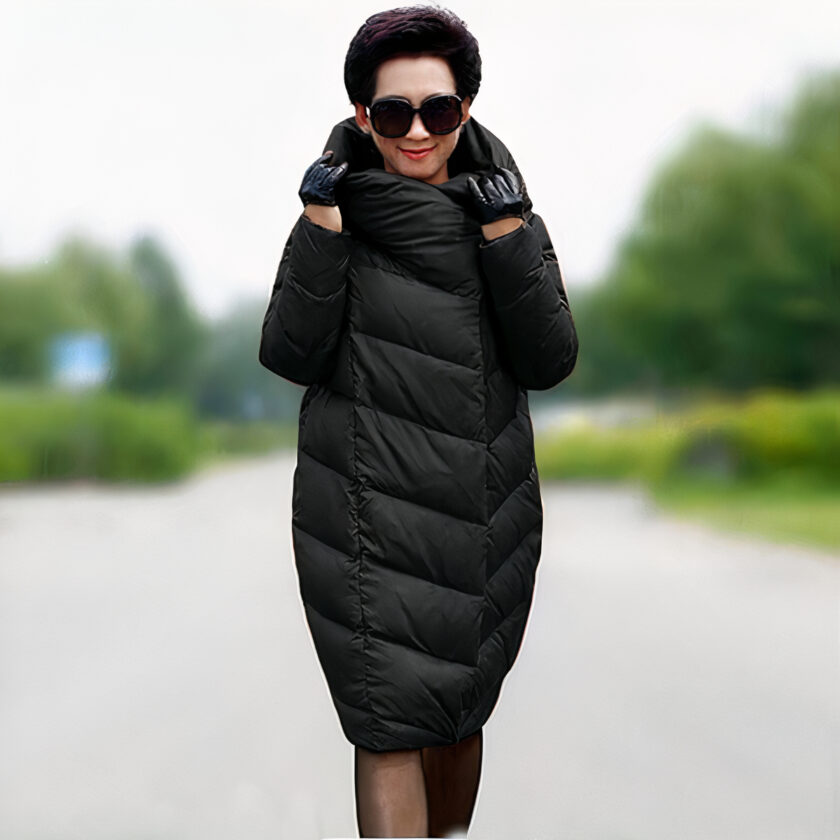 Ältere Frau, die auf einem Feldweg geht und eine schwarze halblange Kokon-Daunenjacke trägt.