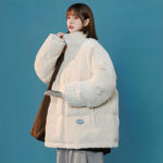 Frau mit einer weißen Oversize-Jacke und einer braunen Handtasche