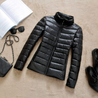 Schwarze, kurze, dünne Daunenjacke mit hohem Kragen für Frauen, die flach am Boden liegt