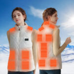 Weiße, ärmellose, elektrisch beheizbare Daunenjacke für Frauen mit einem Schneeberg im Hintergrund