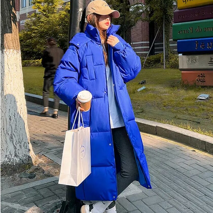 Foto einer Frau mit einer langen blauen Daunenjacke auf der Straße